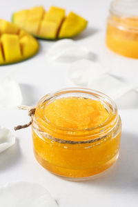 Homemade sugar and mango body scrub in a glass bowl on a white wooden table. cosmetics used with spa 