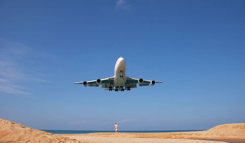 Airplane flying over land against clear blue sky