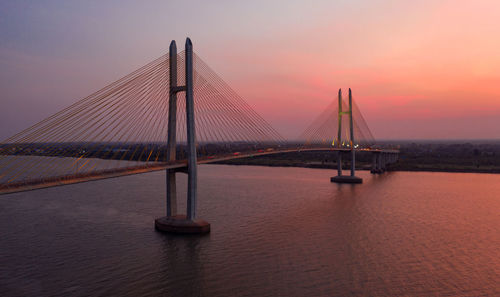 Suspension bridge over sea during sunset