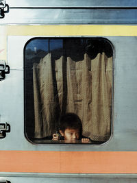 Boy looking away through train window