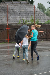 Friends running on street during monsoon