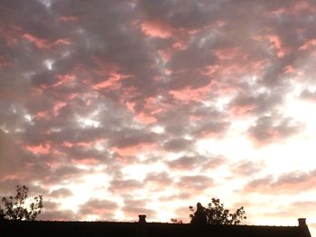 Low angle view of silhouette trees against dramatic sky