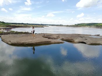 Woman standing at beach against sky