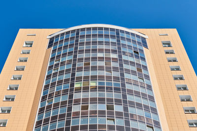 Low angle view of modern building against blue sky