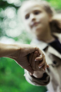 Cropped image of mother holding daughter hand at park