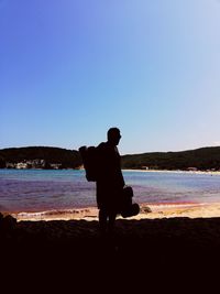 Silhouette man on beach against clear sky