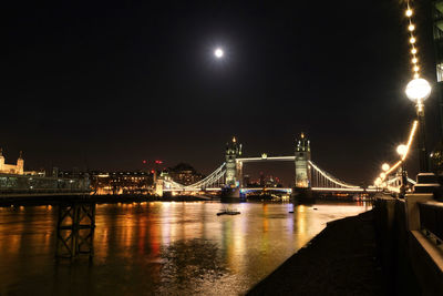 Illuminated bridge over river at night