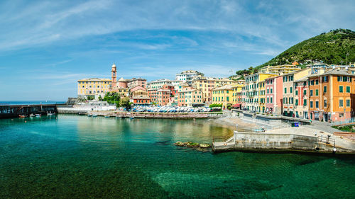 Buildings by sea against sky