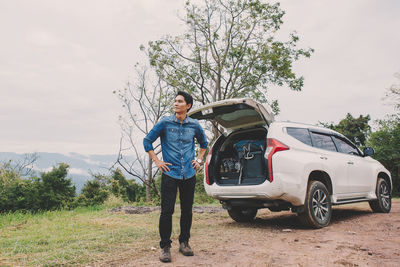 Full length of man standing on car against sky