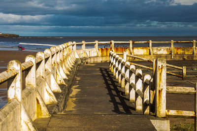 View of wooden pier at beach against sky