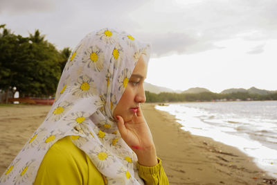 Midsection of woman standing at beach against sky