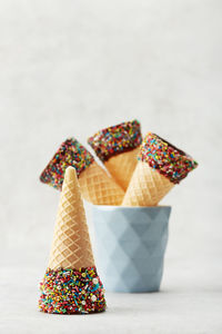 Close-up of ice cream cones on table against white background