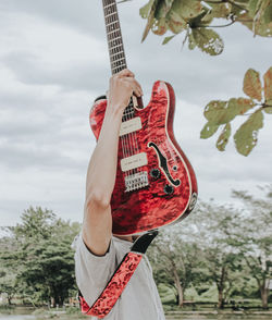 Midsection of man playing guitar against trees