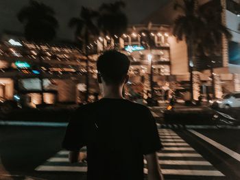 Rear view of man on illuminated street at night