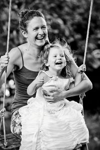 Portrait of a smiling young woman and girl on swing