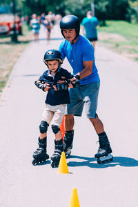 Grandfather holding grandson while rollerblading on road