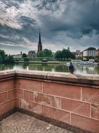 View of building by river against cloudy sky