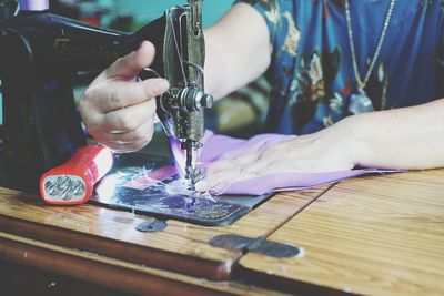 Midsection of woman using sewing machine at home