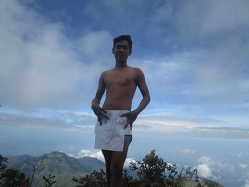 Portrait of young man standing against sky