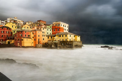 Buildings by sea against sky