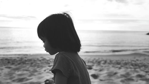 Side view of girl at beach against sky