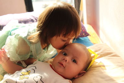 Close-up of cute girl kissing brother on forehead at home