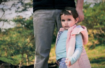 Low section of father with daughter walking outdoors