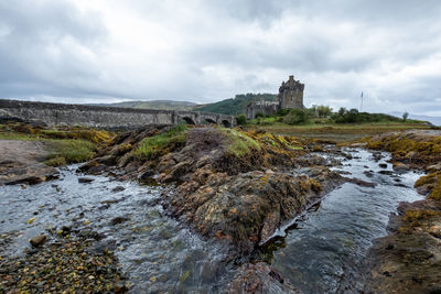 Water flowing through rocks with a castle in the background