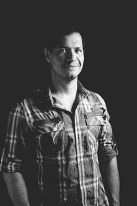 Portrait of mid adult man smiling while standing against black background