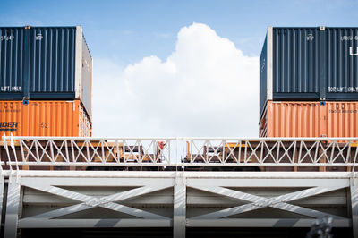 Metallic structure on pier amidst buildings against sky