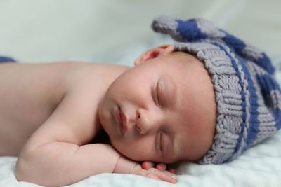 Close-up of baby girl lying on bed at home