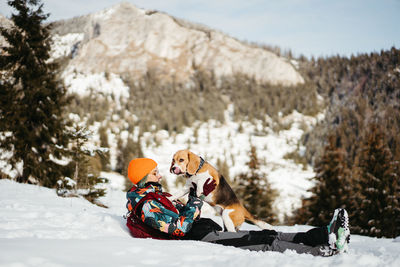 Portrait of woman with dog on snow covered field