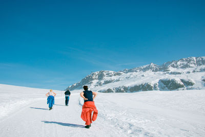 Rear view of people walking on snow covered land