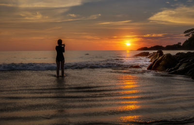 Silhouette woman standing on beach during sunset