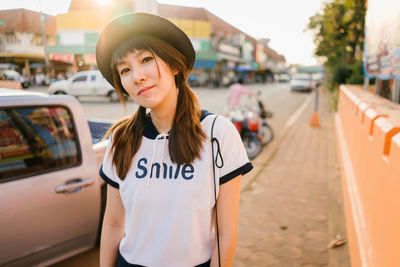 Portrait of young woman standing on sidewalk