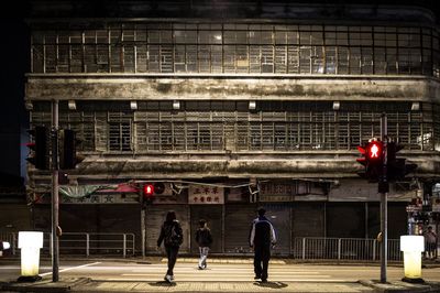 Rear view of people crossing street at night