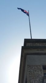 Low angle view of flag on building against clear sky