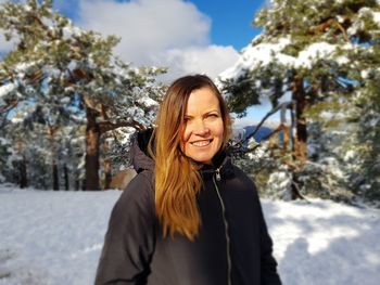 Portrait of smiling young woman standing in snow