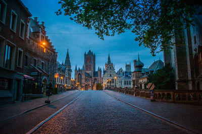 Street amidst buildings in city at dusk