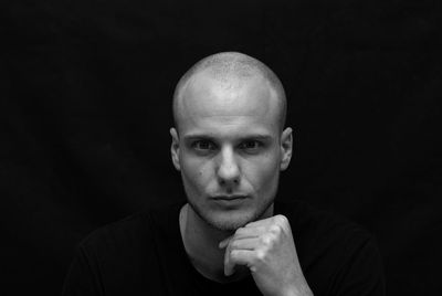 Portrait of man with shaved head against black background