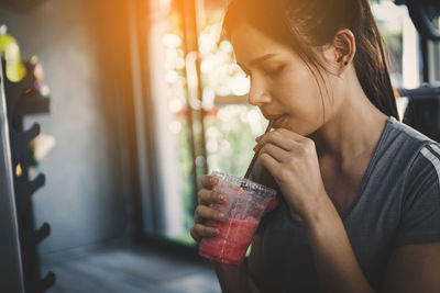 Portrait of woman drinking water from window