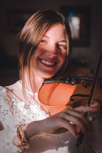 Smiling young woman looking away while playing violin