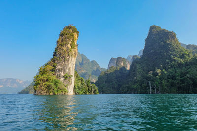 Scenic view of sea and mountains against clear blue sky