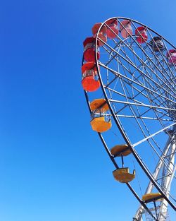 Low angle view of ferris wheel against clear blue sky