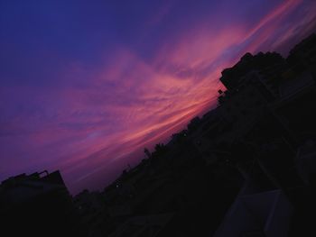 Low angle view of silhouette buildings against sky at sunset