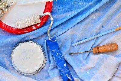 Directly above shot of painting equipment on blue textile