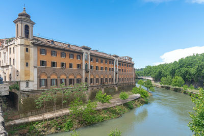 Buildings by river against clear blue sky