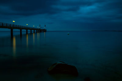 Pier at night with light trails in the water