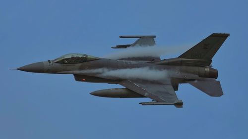 Low angle view of airplane flying against clear blue sky