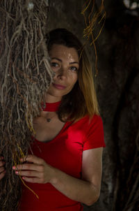 Portrait of woman standing by tree trunk